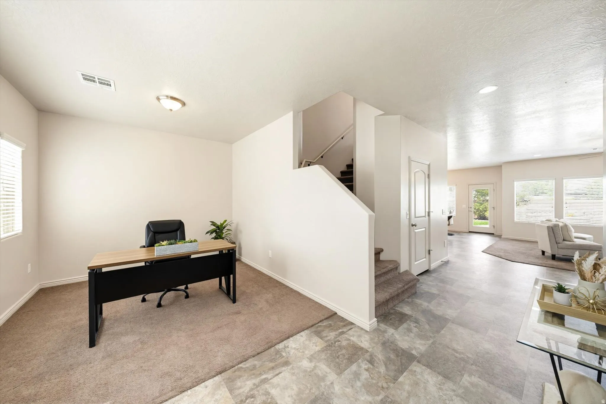 Home office with healthy amount of natural light, light carpet, and stone finish flooring