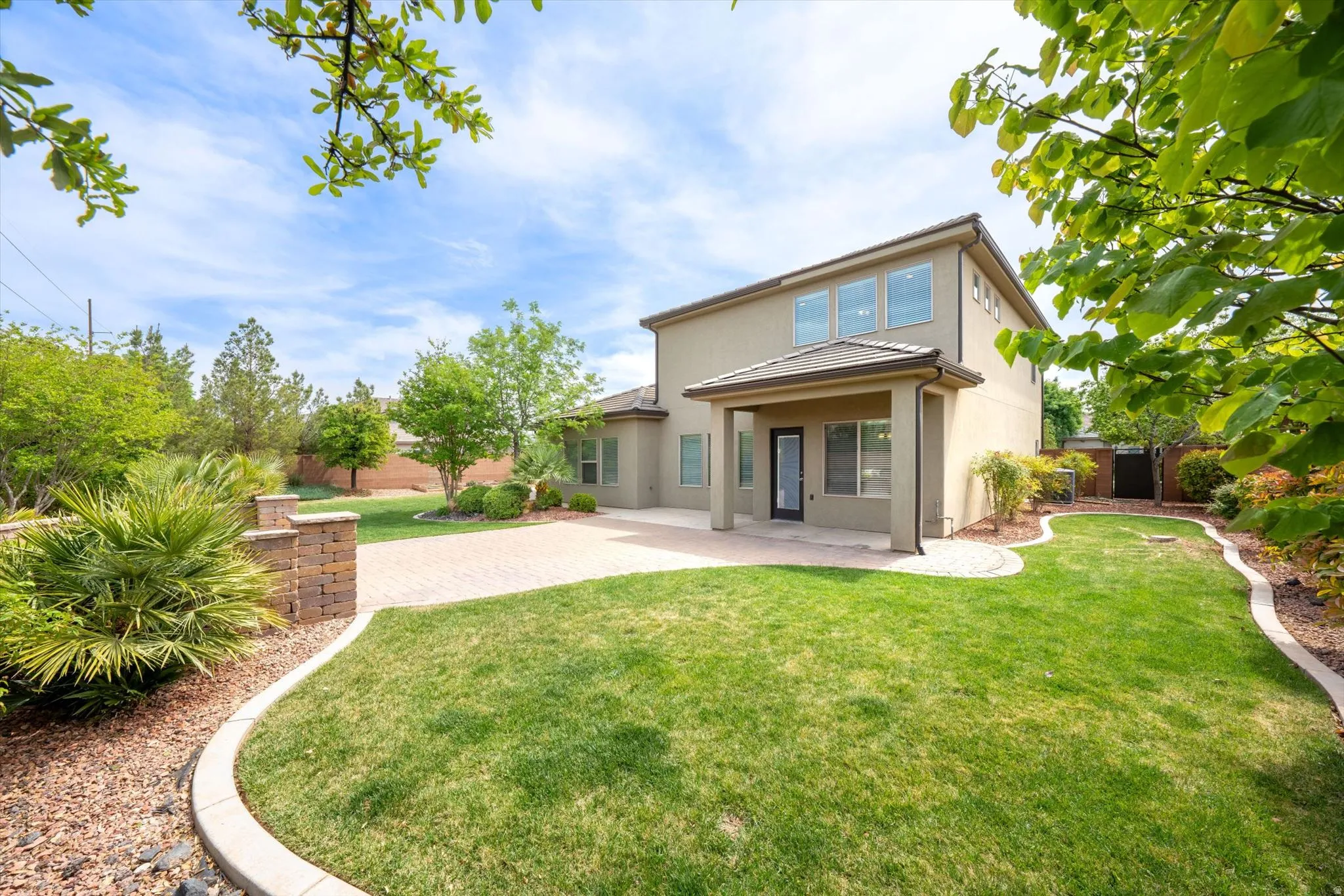Back of property featuring a fenced backyard, stucco siding, and a patio