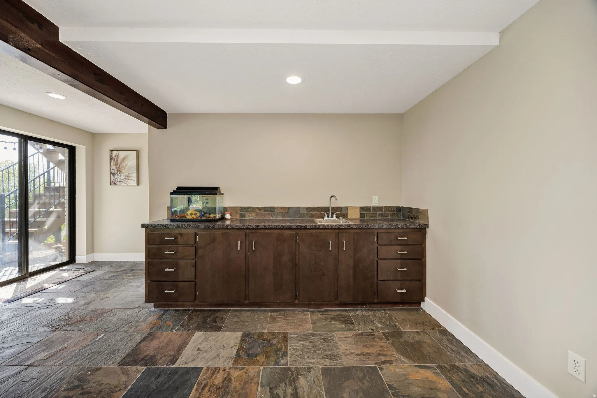 Bar featuring dark wood finish cabinetry, beamed ceiling, recessed lighting, and stone tile floors