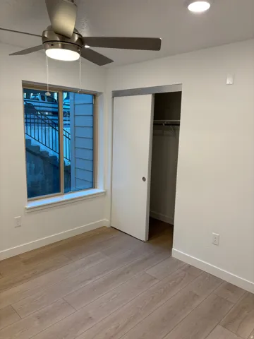 Unfurnished bedroom featuring light wood-type flooring, ceiling fan, and a closet
