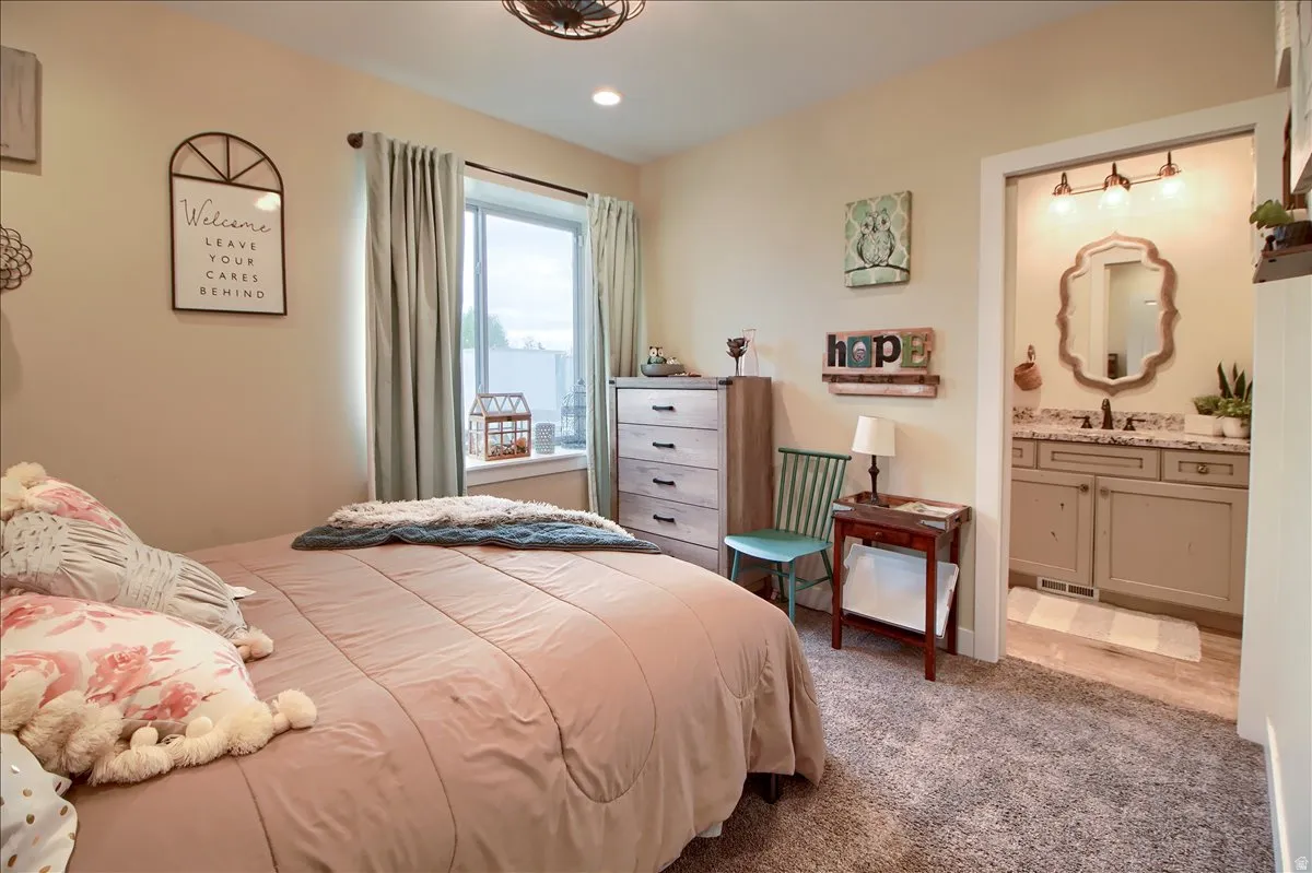 Carpeted bedroom with ensuite bath and recessed lighting