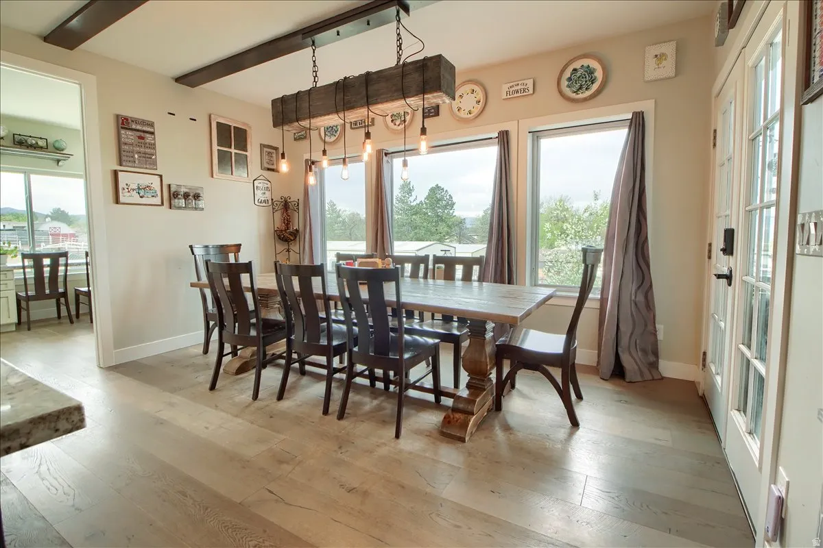 Dining space featuring light wood-type flooring, healthy amount of natural light, and beam ceiling