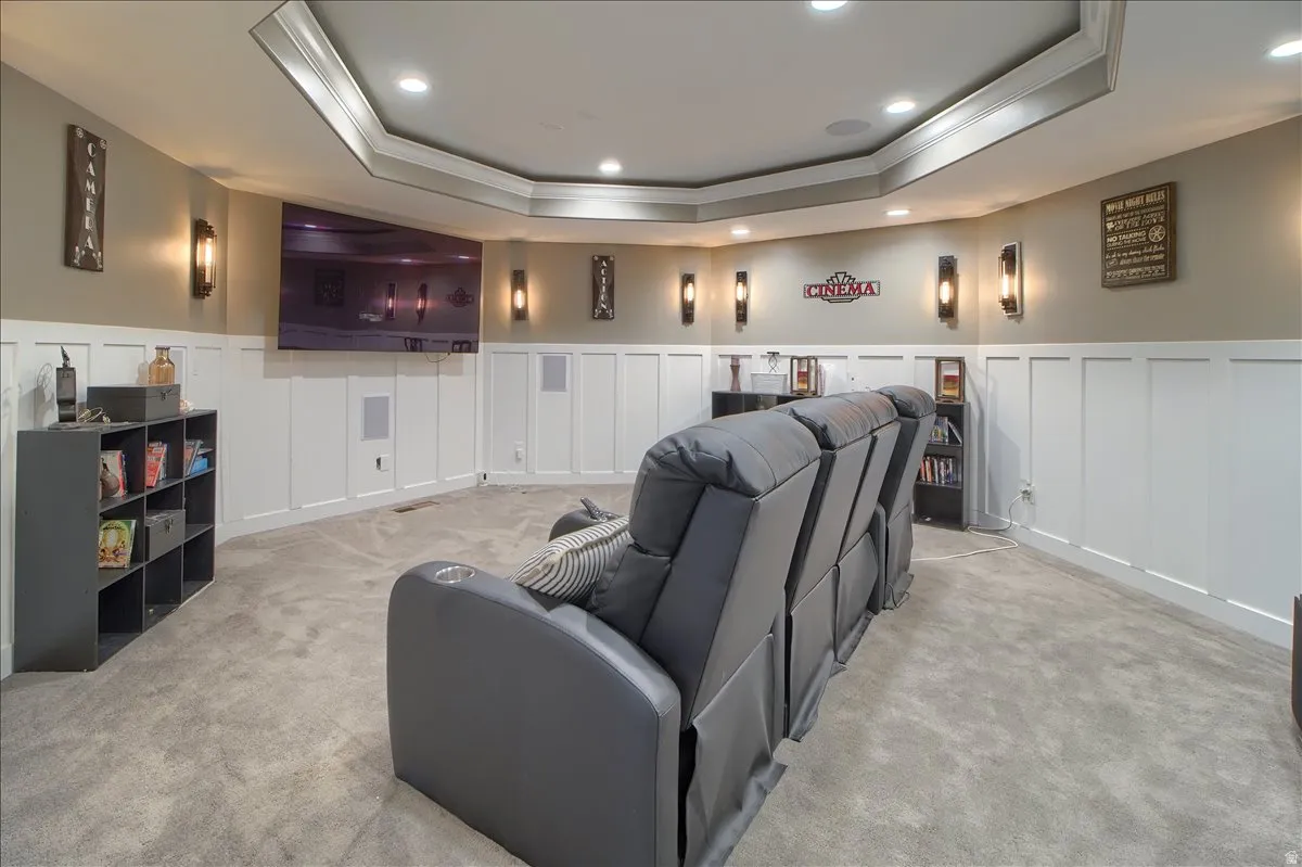 Cinema featuring a decorative wall, wainscoting, ornamental molding, a tray ceiling, and recessed lighting