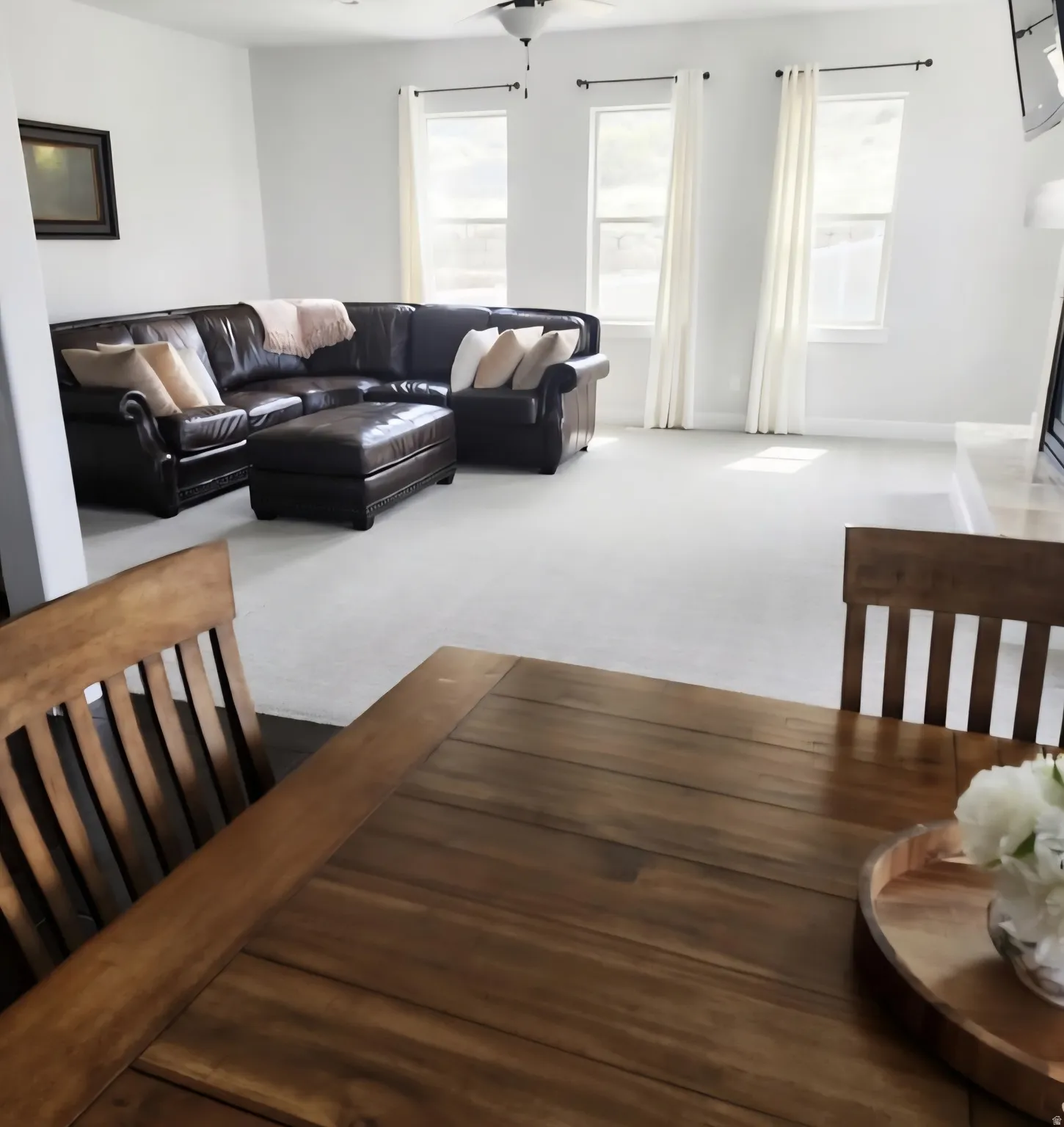 Open-concept living area featuring light-colored carpeting and white wall finishes