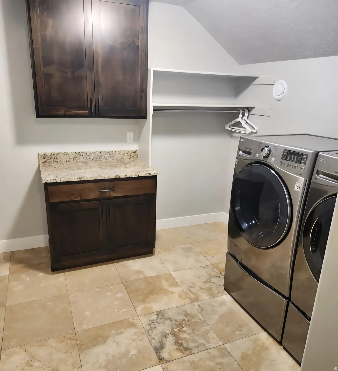 Utility room featuring tile flooring, built-in cabinetry, a countertop, and an integrated clothes hanging rod with shelving