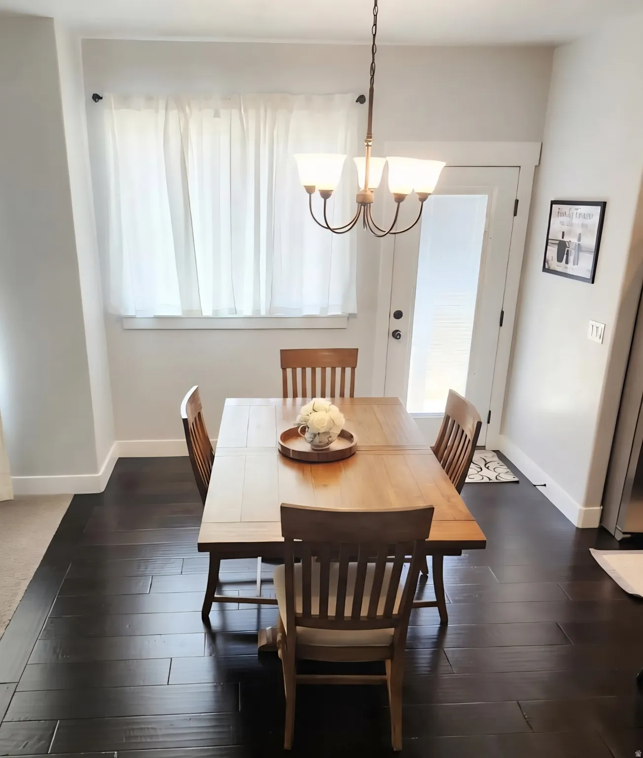Dining area featuring dark wood-finish flooring, a contemporary chandelier, and a transom door
