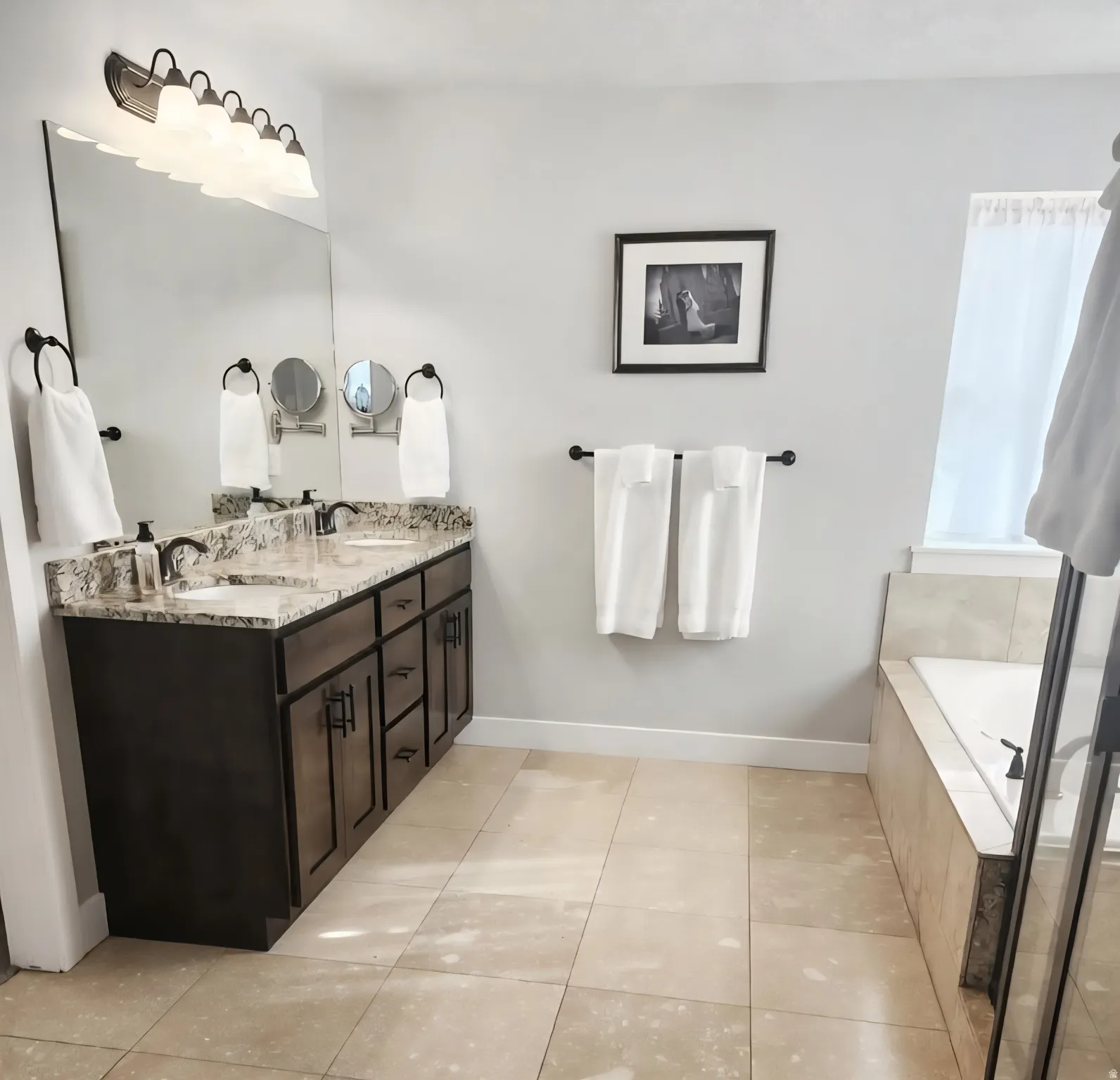 Double vanity with a granite countertop, undermount sinks, and dark wood cabinetry