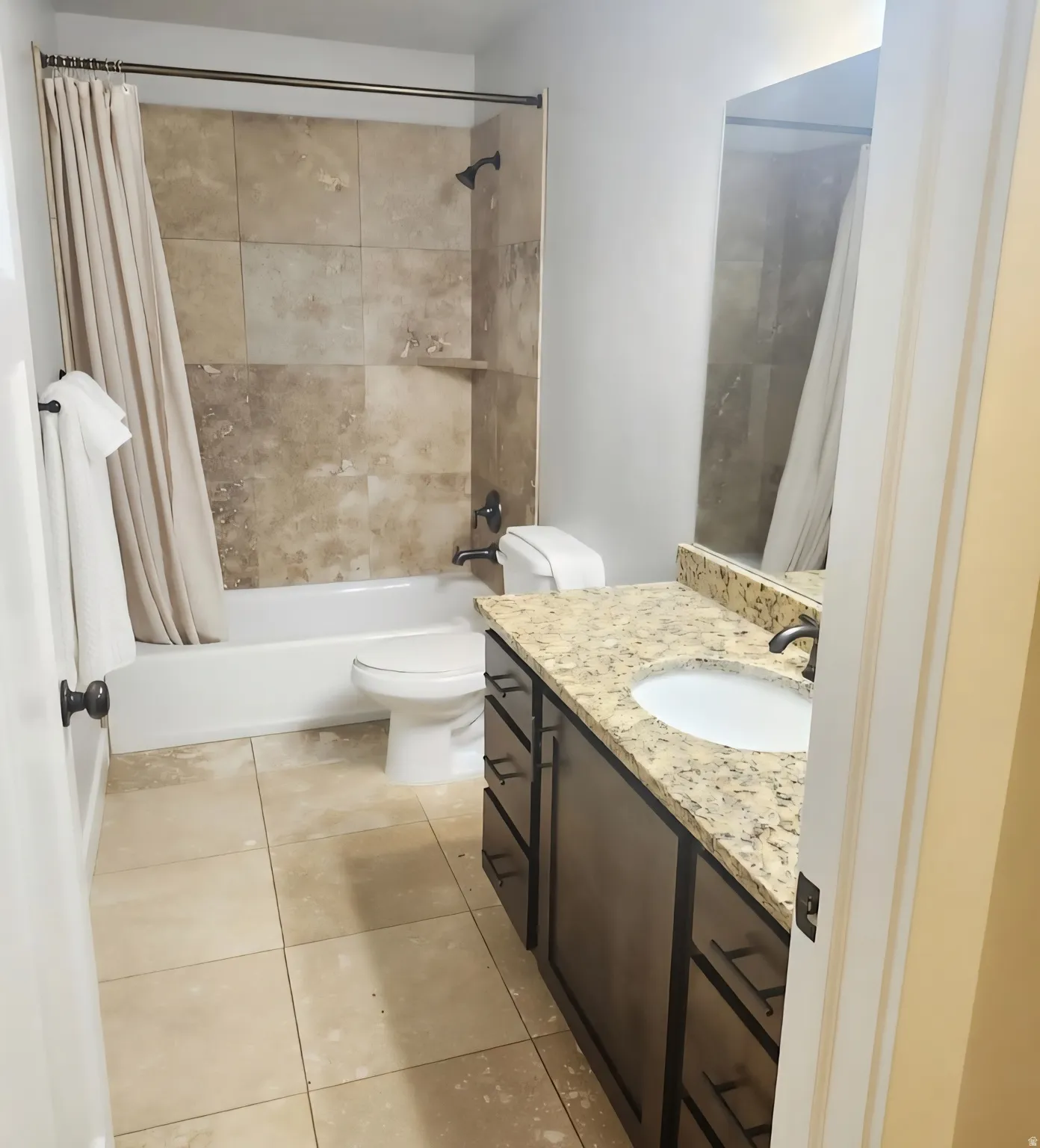Bathroom featuring a vanity with granite-style countertop, integrated sink, and dark wood-finish cabinetry with multiple drawers