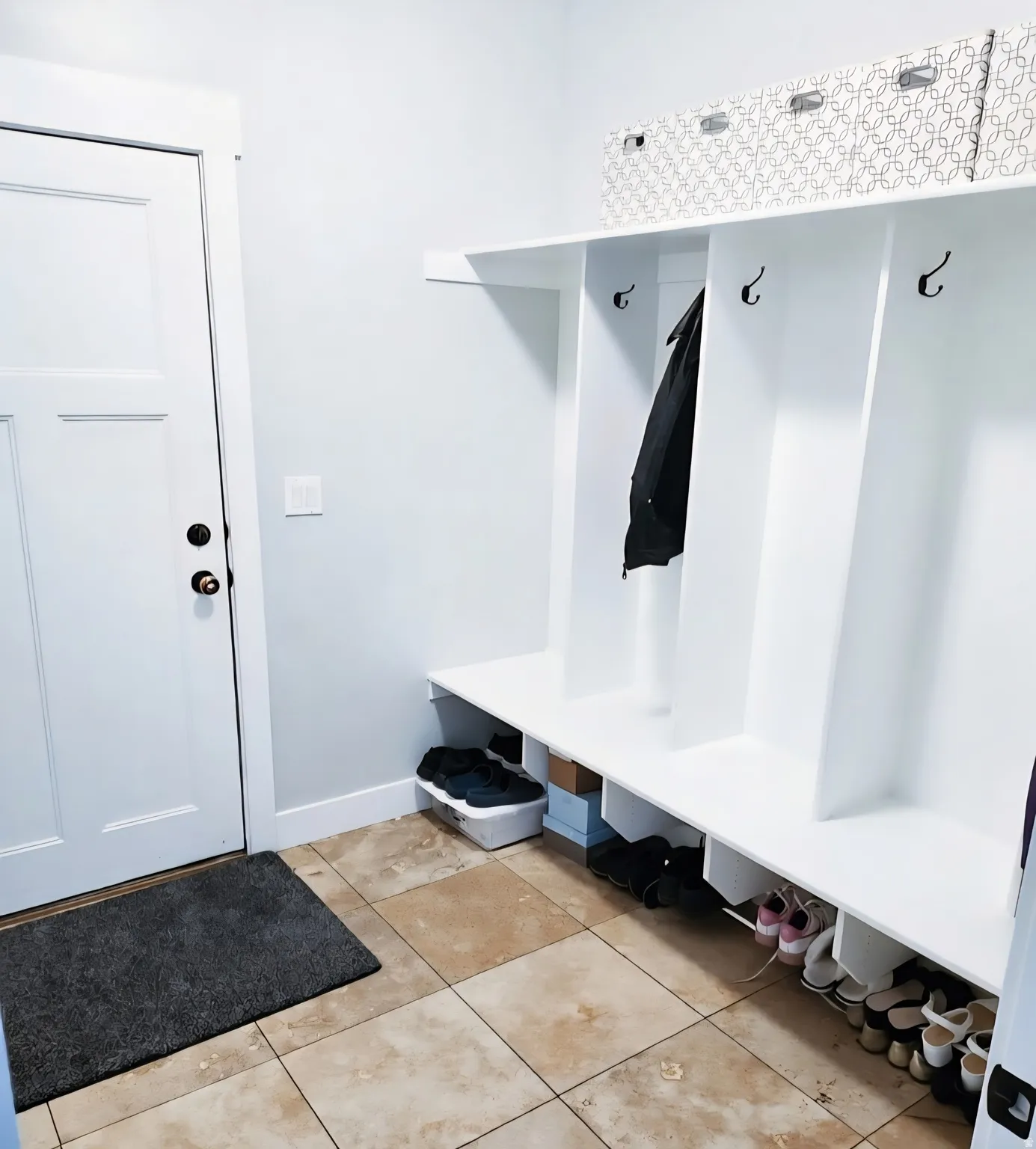 Built-in white cubby storage featuring upper shelving and individual coat hooks