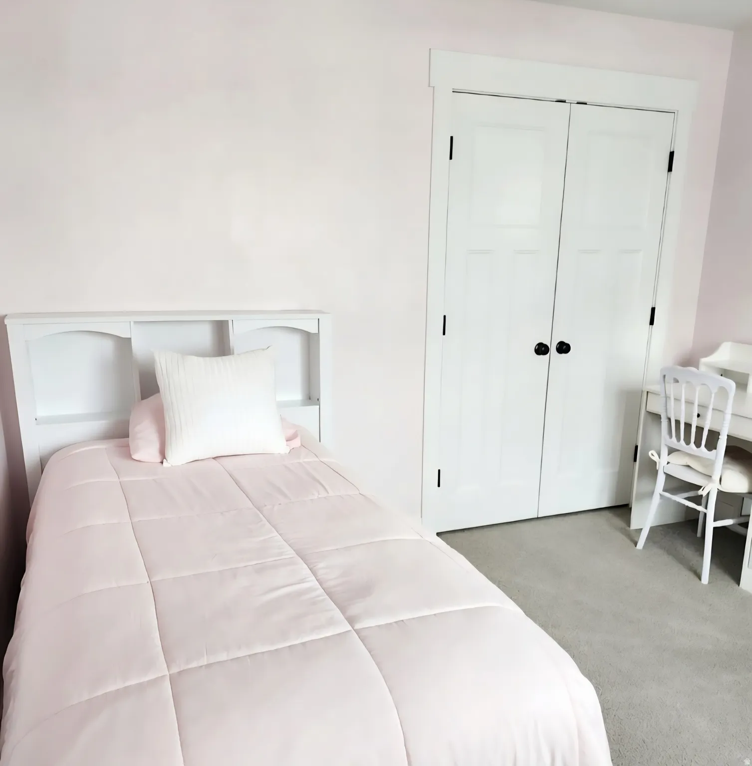 Bedroom featuring light wall color, carpet flooring, and white bi-fold closet doors with dark hardware