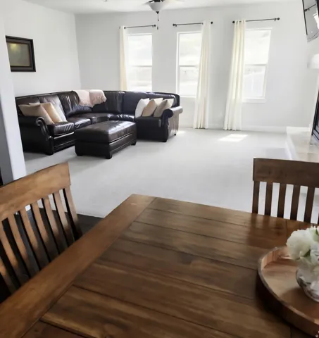 Open-concept living area featuring light-colored carpeting and white wall finishes