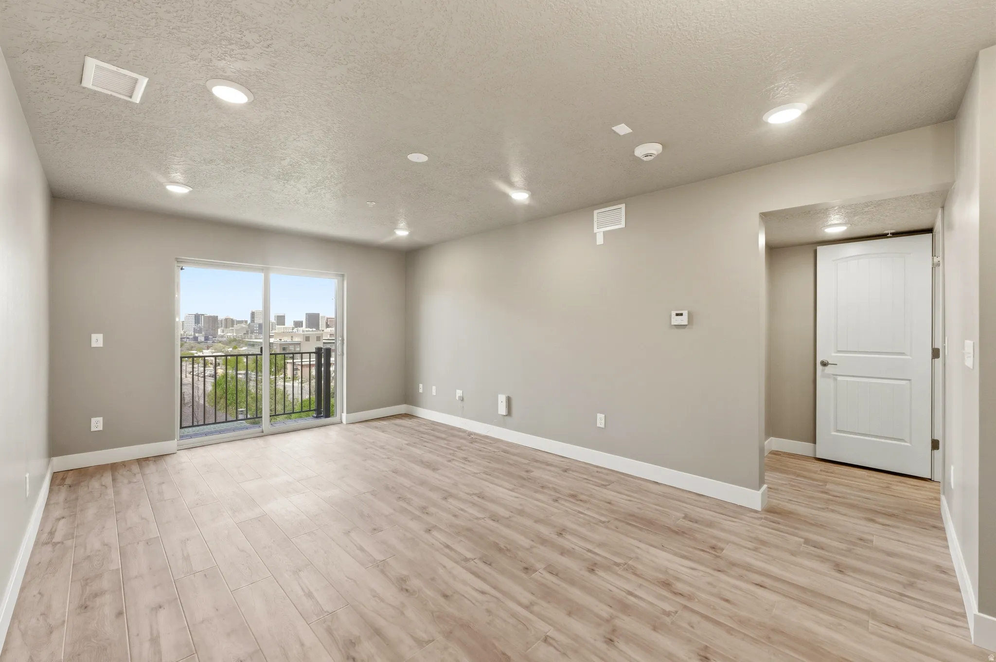 Unfurnished room featuring a textured ceiling, light wood-style flooring, recessed lighting, and a skyline view