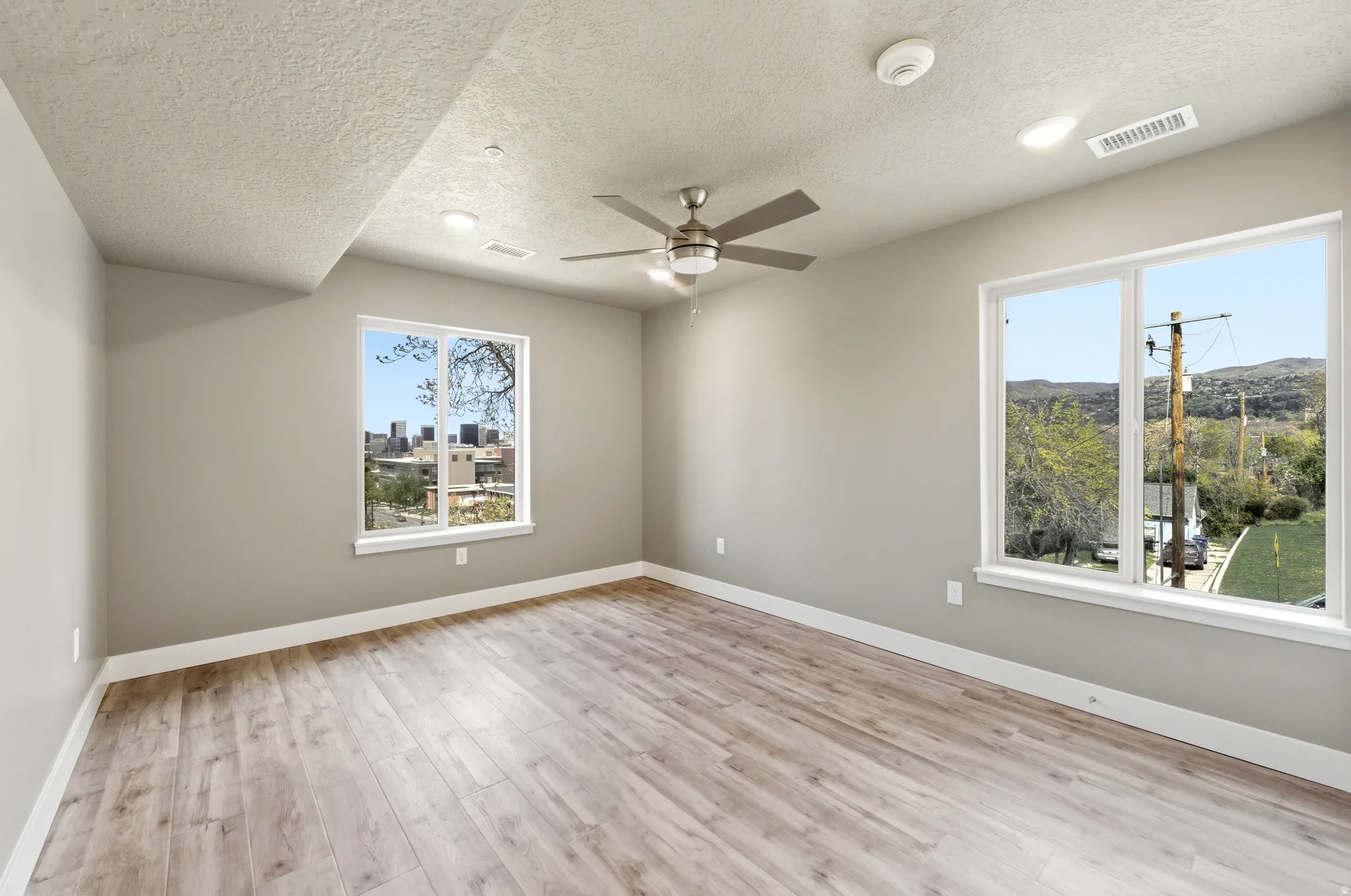 Bedroom featuring light wood finished floors, ceiling fan, a textured ceiling, and a smoke detector