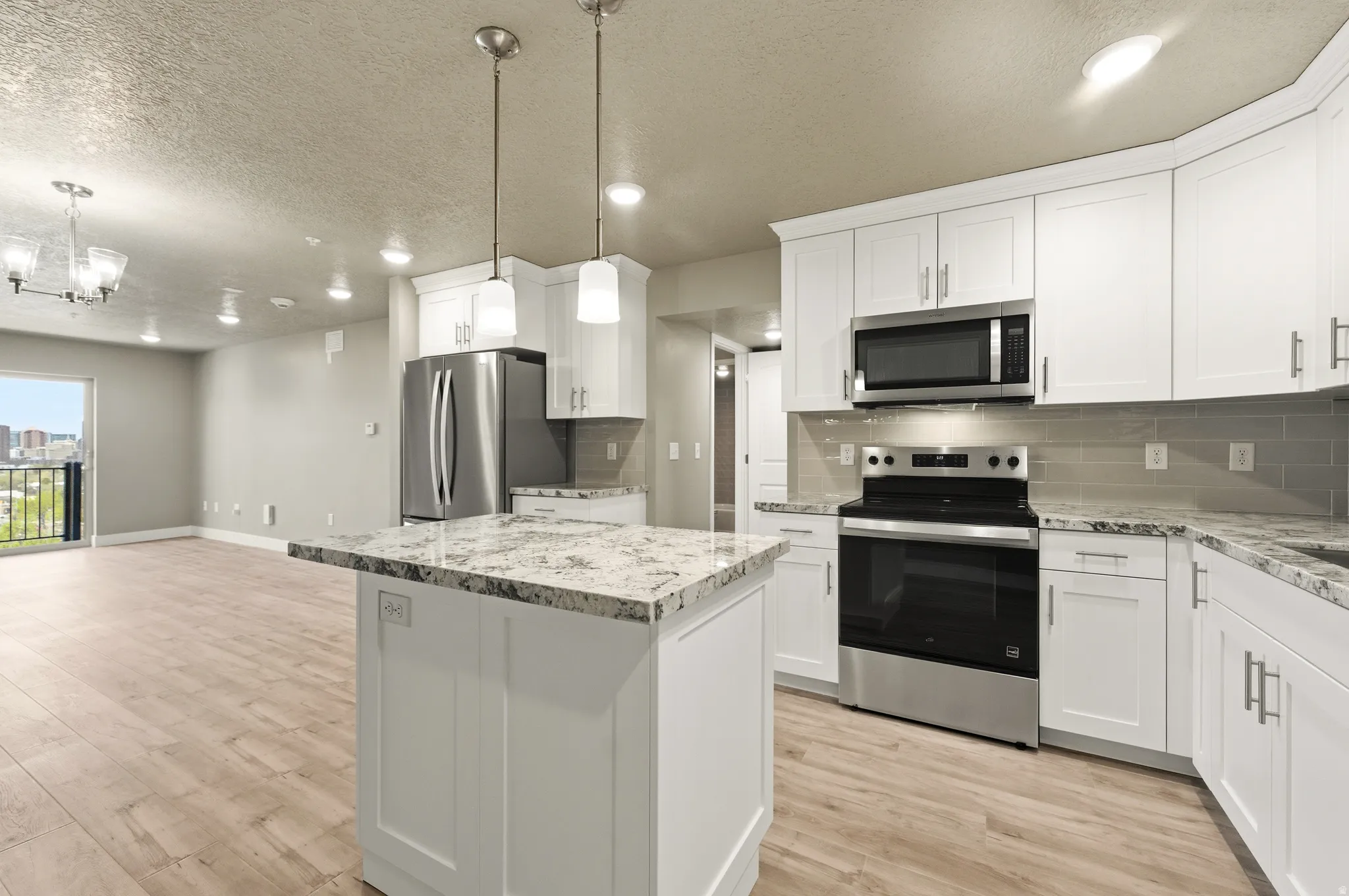 Kitchen with stainless steel appliances, white cabinetry, light wood finished floors, and a textured ceiling