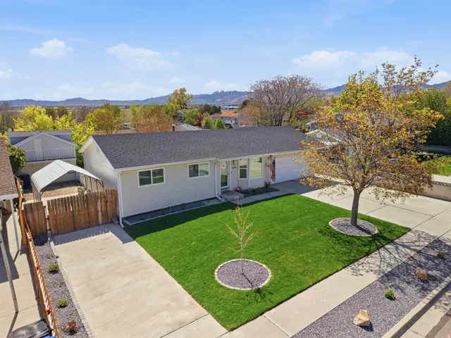 Ranch-style home featuring concrete driveway, a mountain view, roof with shingles, and a residential view
