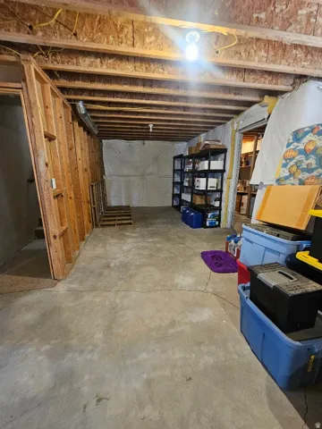 Unfinished basement featuring exposed wood joists, concrete flooring, and partial wood framing for future customization