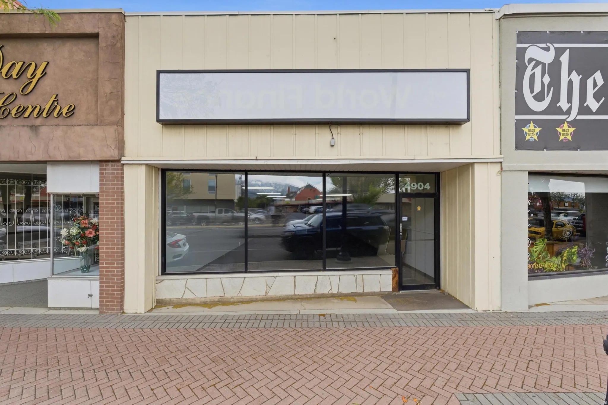 Commercial storefront featuring large display windows, a single-door entry, a prominent sign area, and a stone-finish facade base