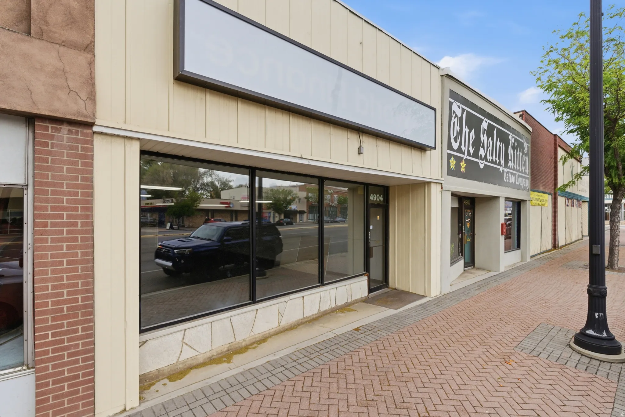 Commercial storefront with large display windows, a neutral-toned facade, and a prominent blank sign space