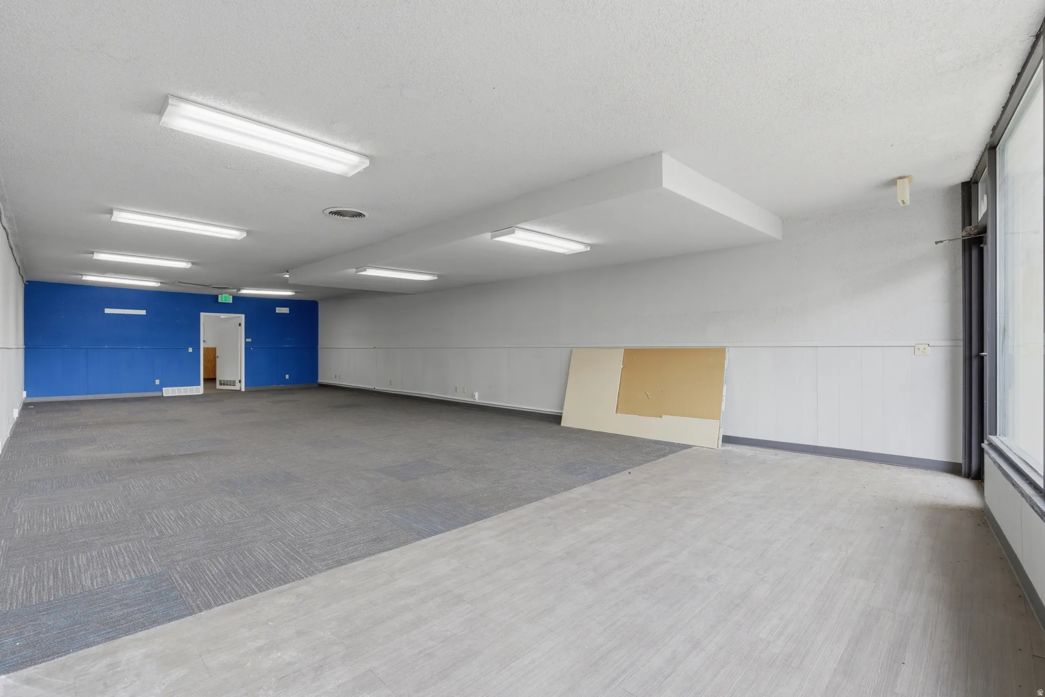 Spacious room featuring partial wood-finish flooring and partial carpet flooring