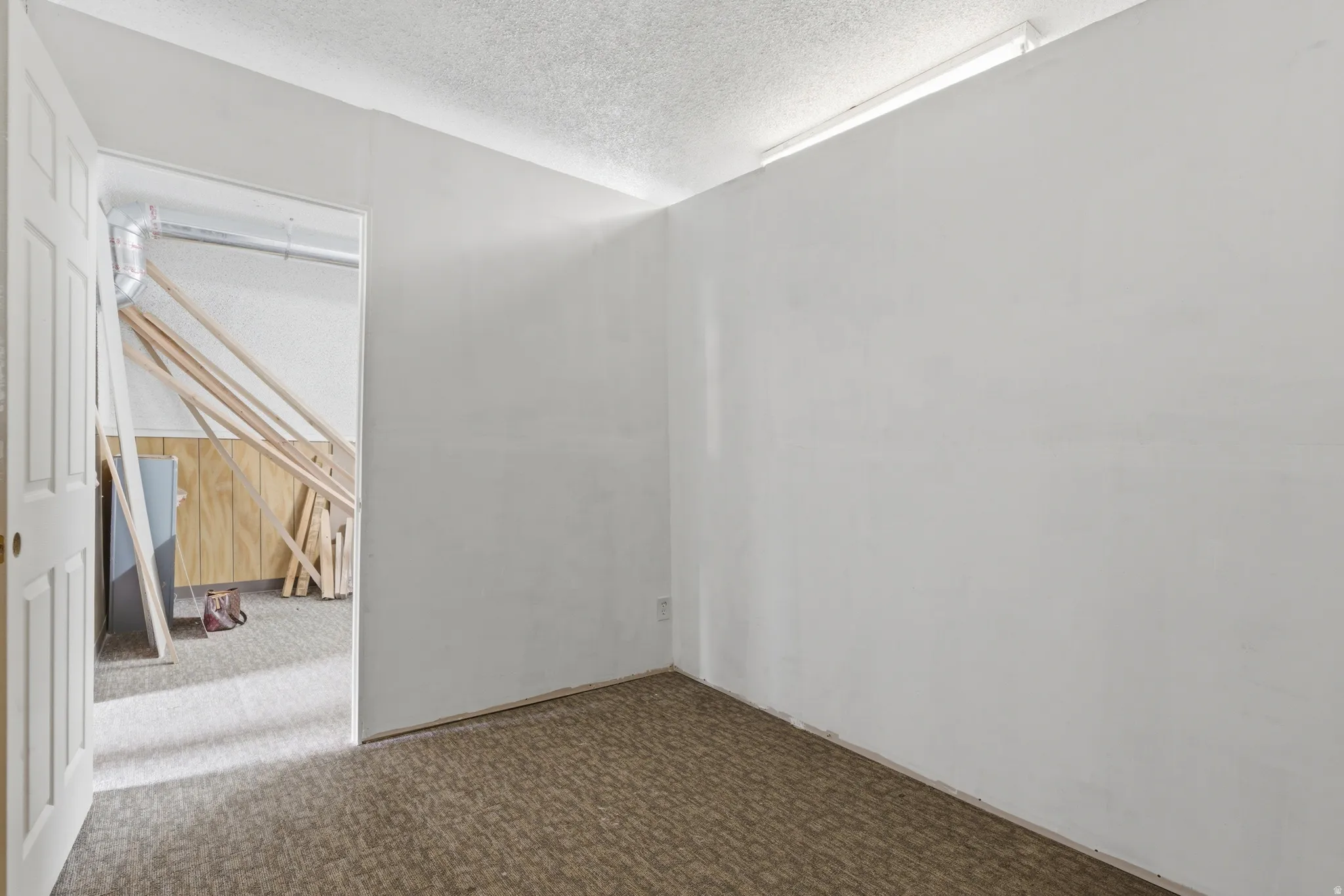 Carpeted room with white painted walls and a textured ceiling