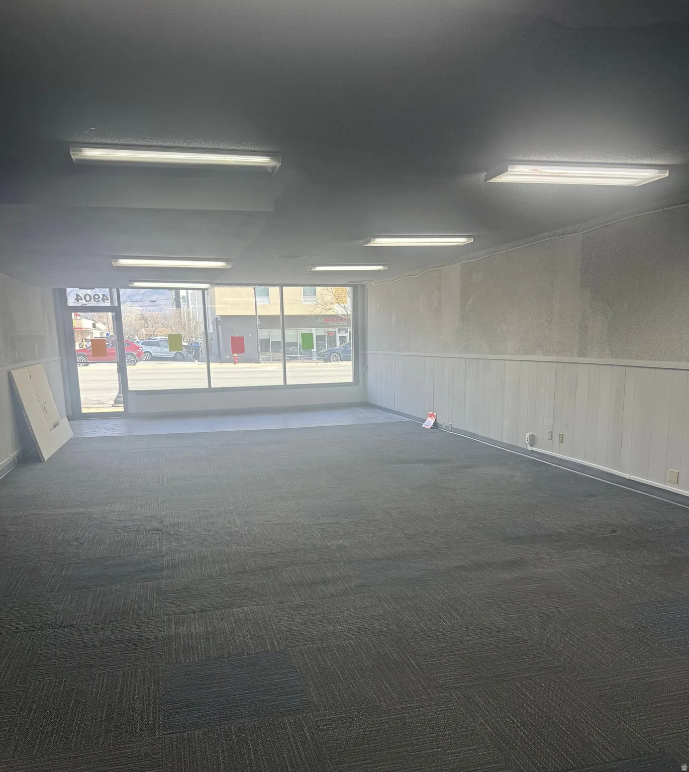 Unfurnished room featuring a wainscoted wall and dark colored carpet