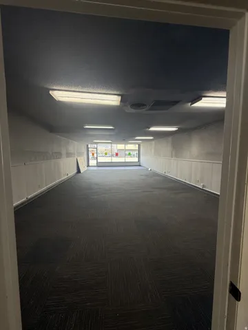 Hallway featuring dark colored carpet and a wainscoted wall