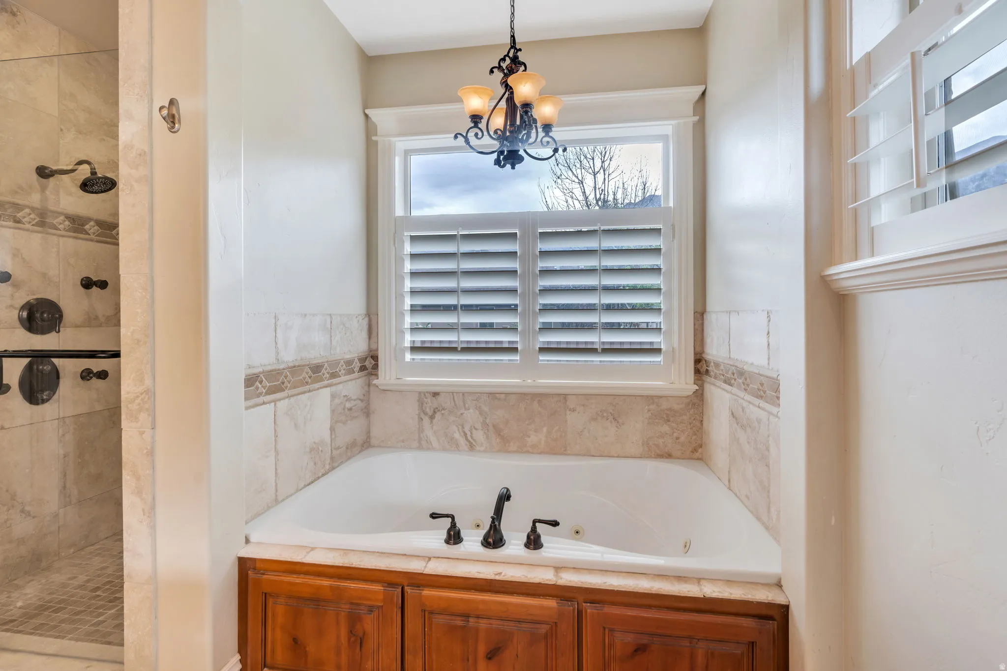 Full bath with a tub with jets, a tile shower, and suspended lighting