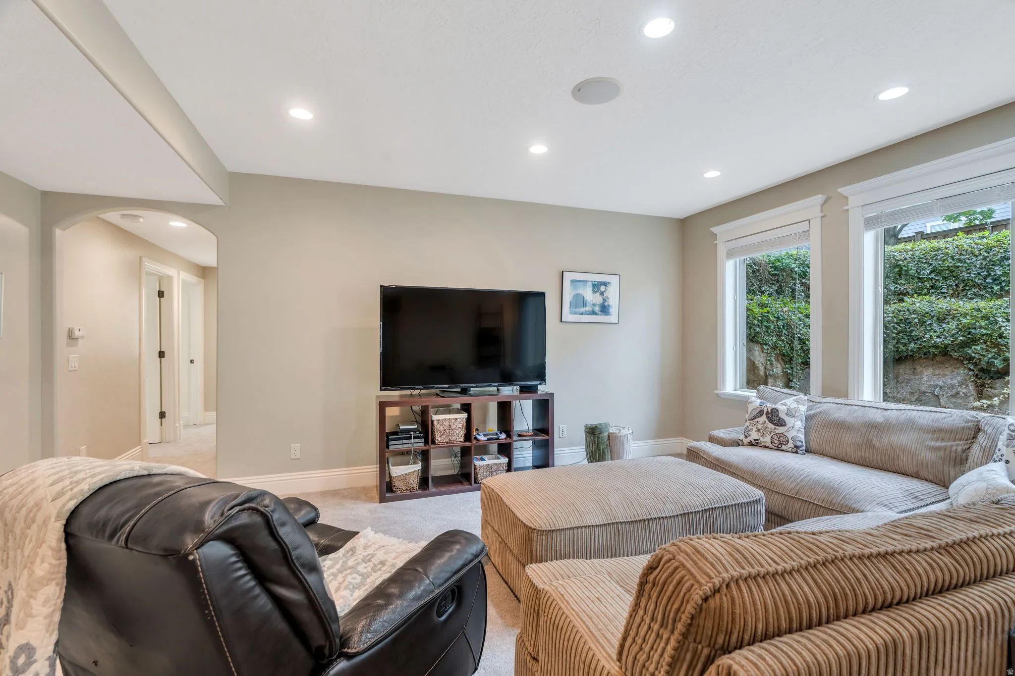 Living area featuring arched walkways, light carpet, and recessed lighting