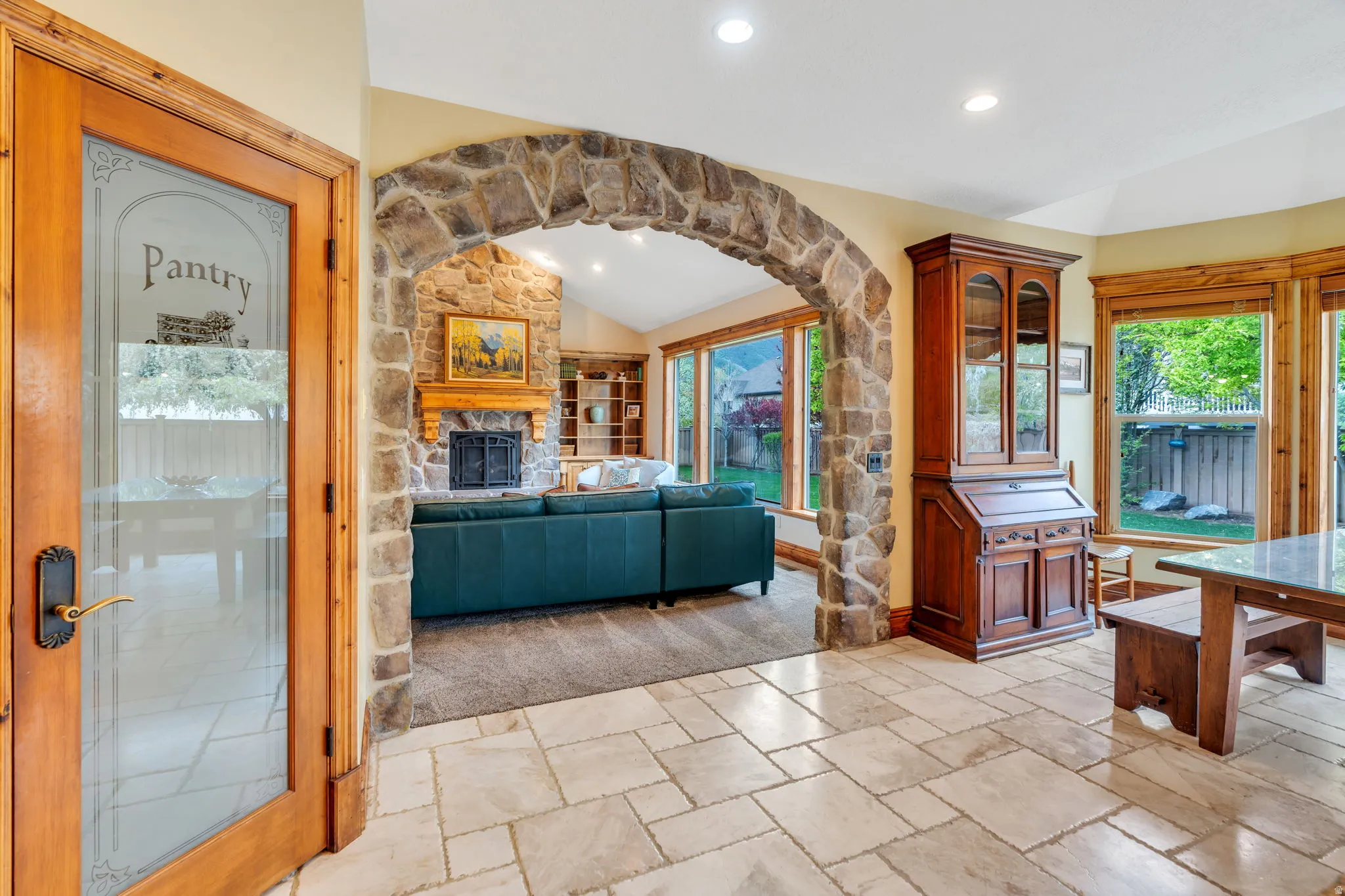 Living room featuring vaulted ceiling, stone tile floors, recessed lighting, arched walkways, and a fireplace