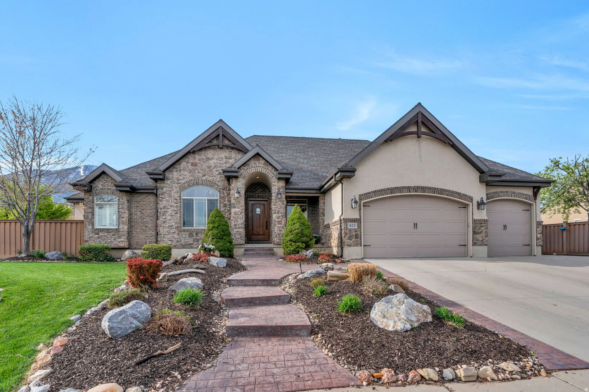 French country home with an attached garage, concrete driveway, and stucco siding