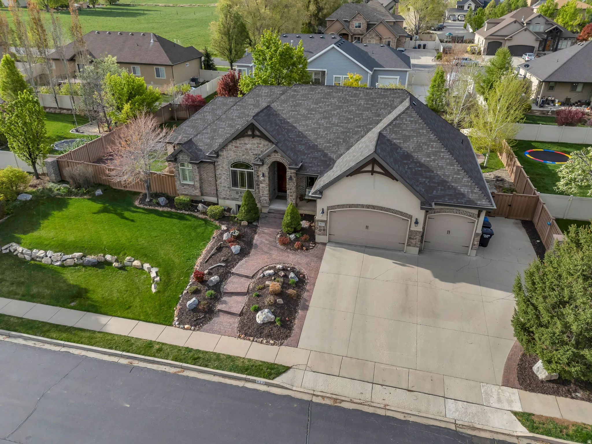 French country style house with stone siding, a garage, stucco siding, concrete driveway, and a residential view