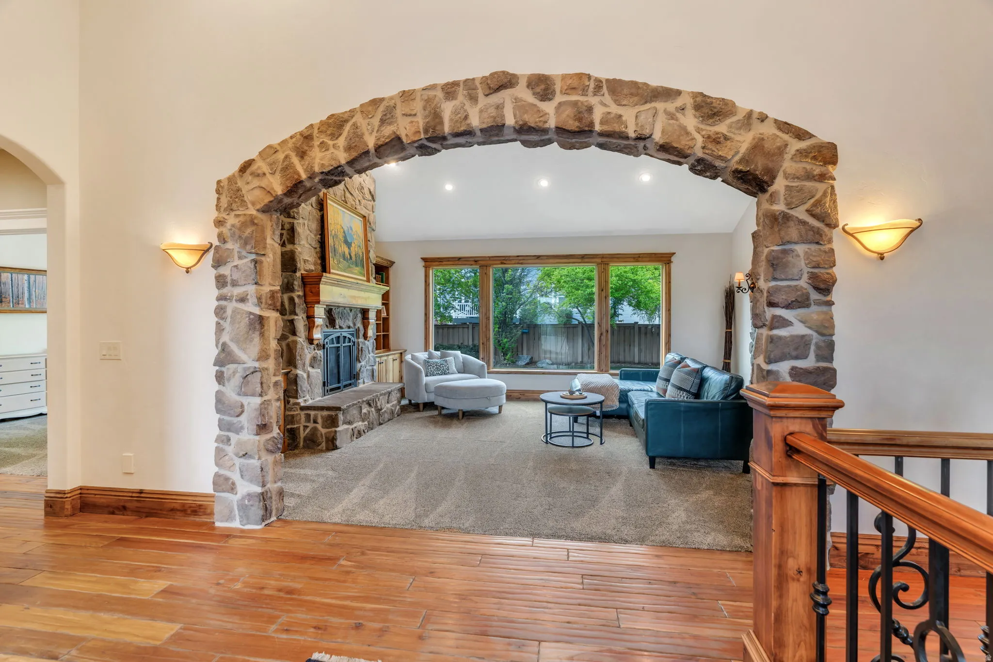 Living room with arched walkways, a stone fireplace, and hardwood / wood-style flooring