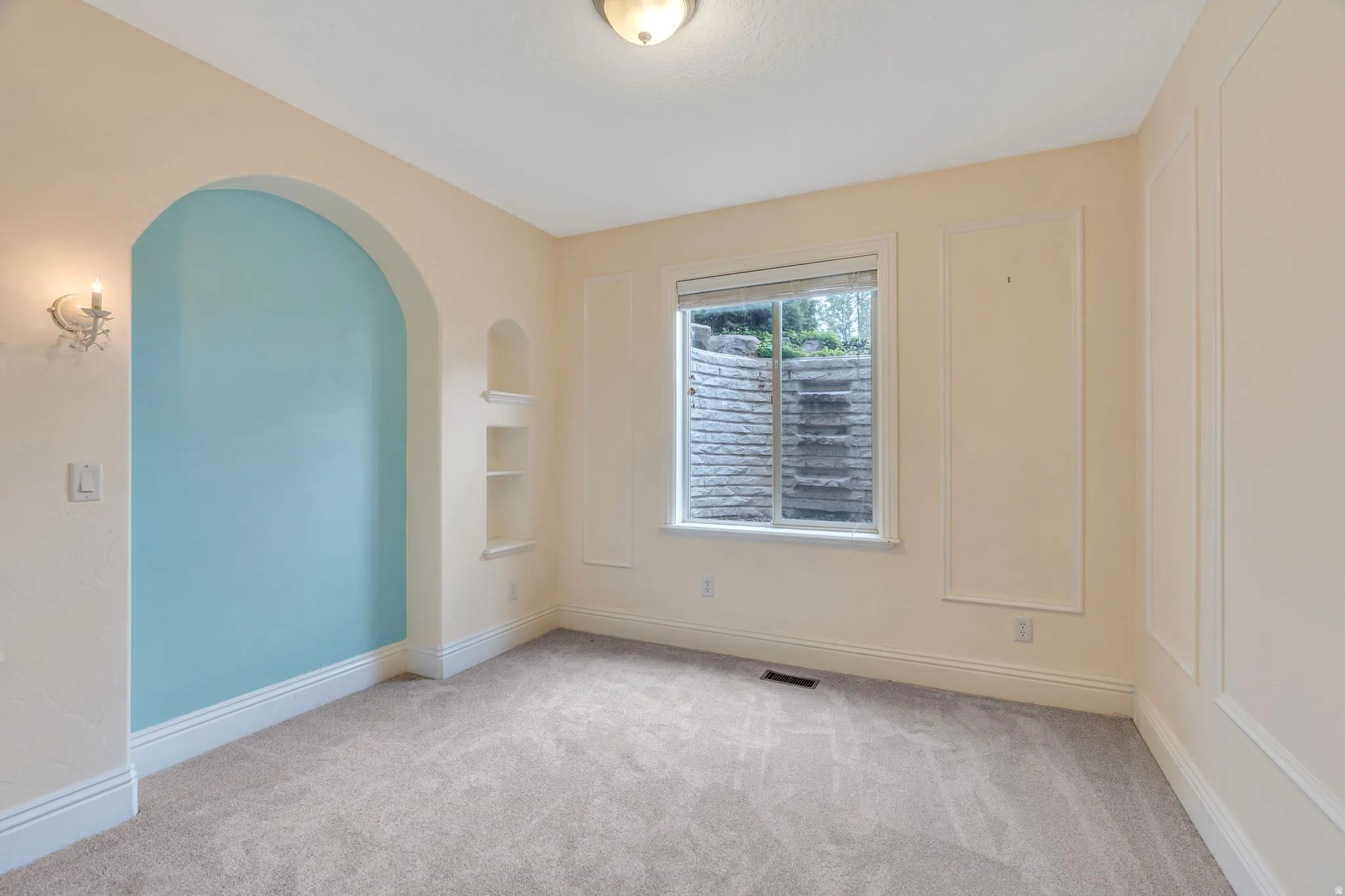 Unfurnished room with light colored carpet and arched walkways