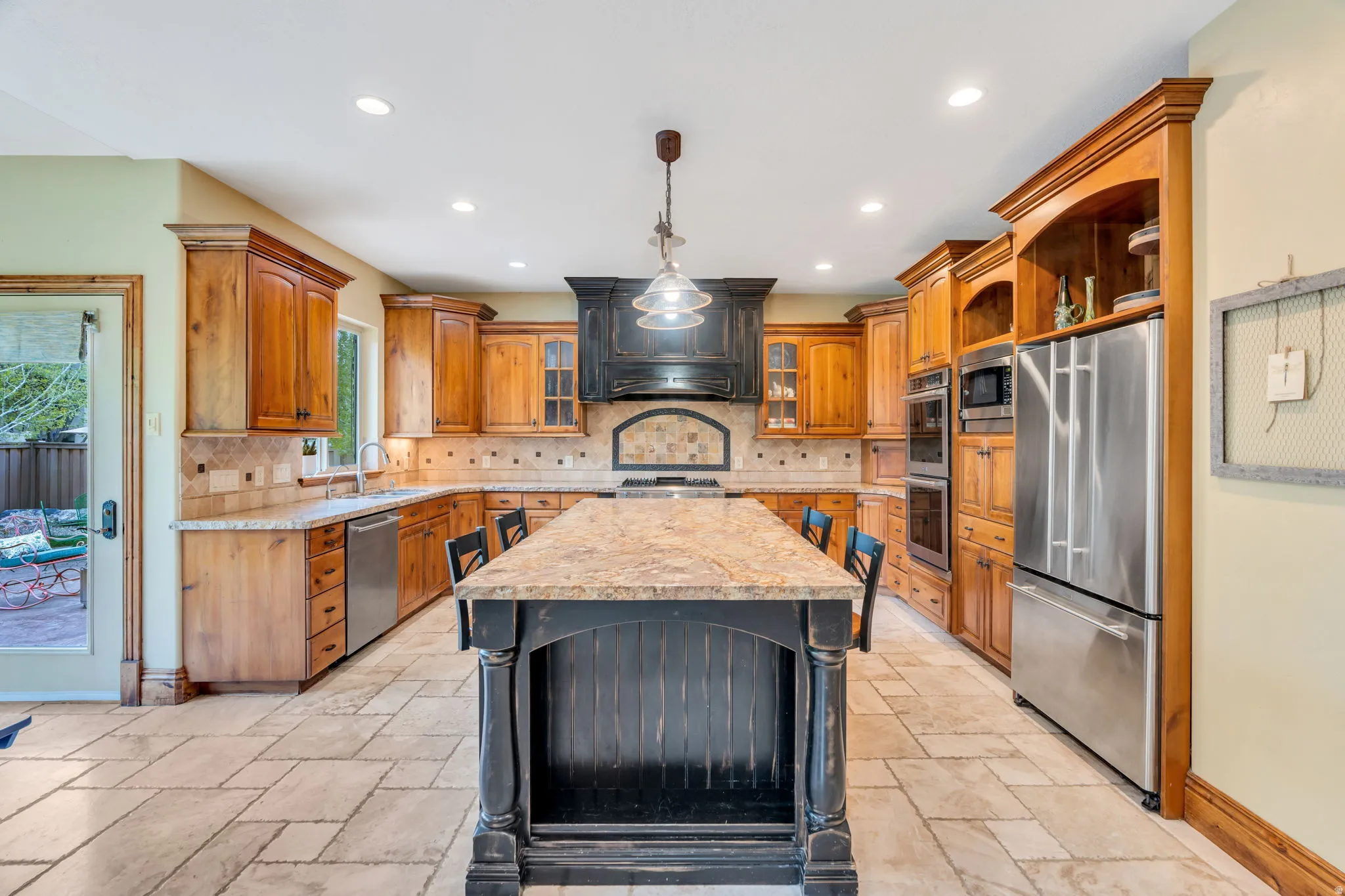 Kitchen featuring stainless steel appliances, backsplash, a center island, glass insert cabinets, and wood finish cabinets