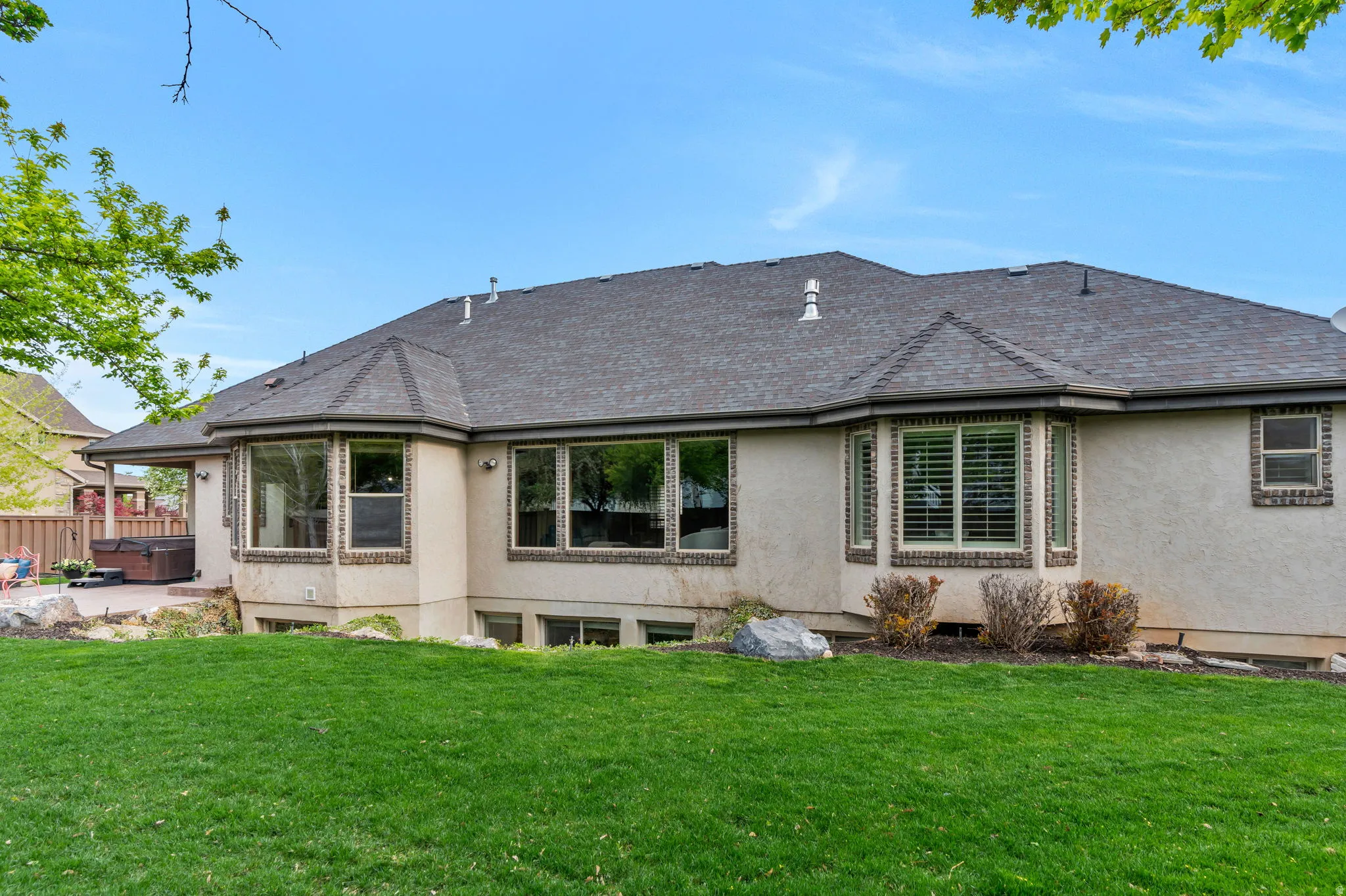 Rear view of house with a lawn, a patio area, and stucco siding