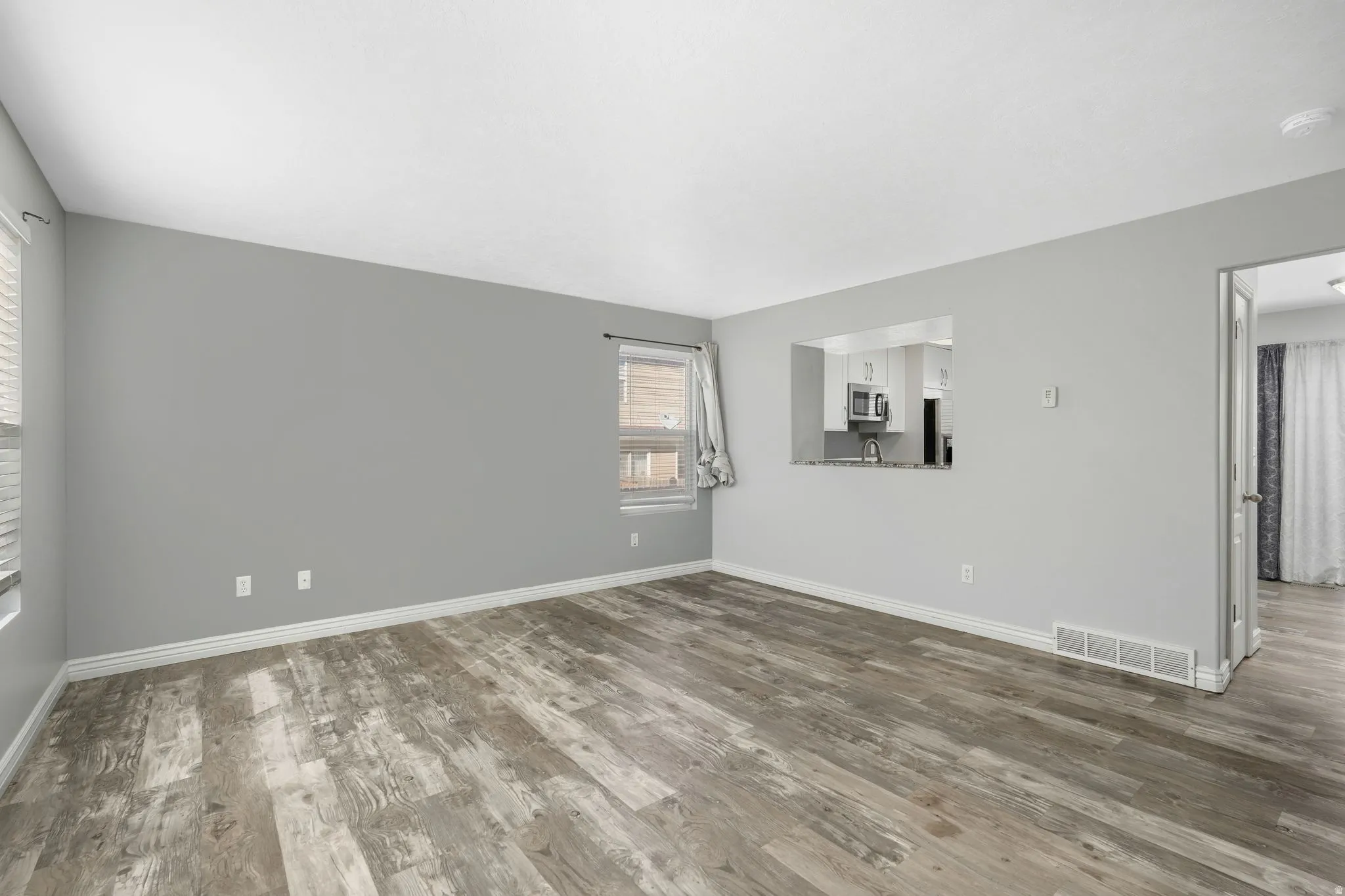 Spare room with dark wood-type flooring and baseboards
