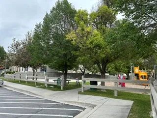 Community playground featuring a sand surface, colorful play structures, and mature shade trees
