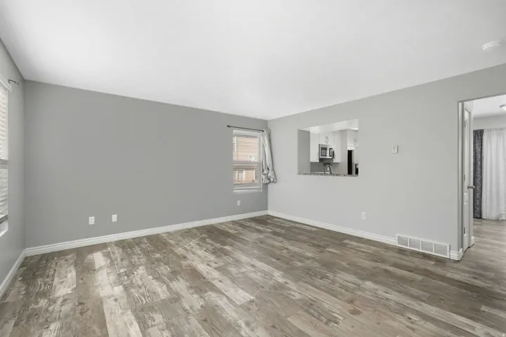 Spare room with dark wood-type flooring and baseboards