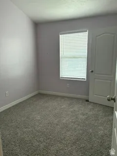 Room featuring purple-toned walls, gray-flecked carpeting, white trim, and a window with horizontal blinds