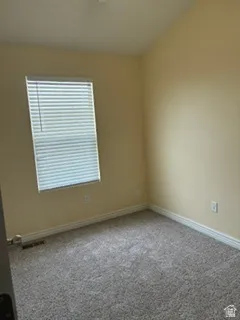 Carpeted room featuring a single window with horizontal blinds, neutral wall paint, and white baseboards