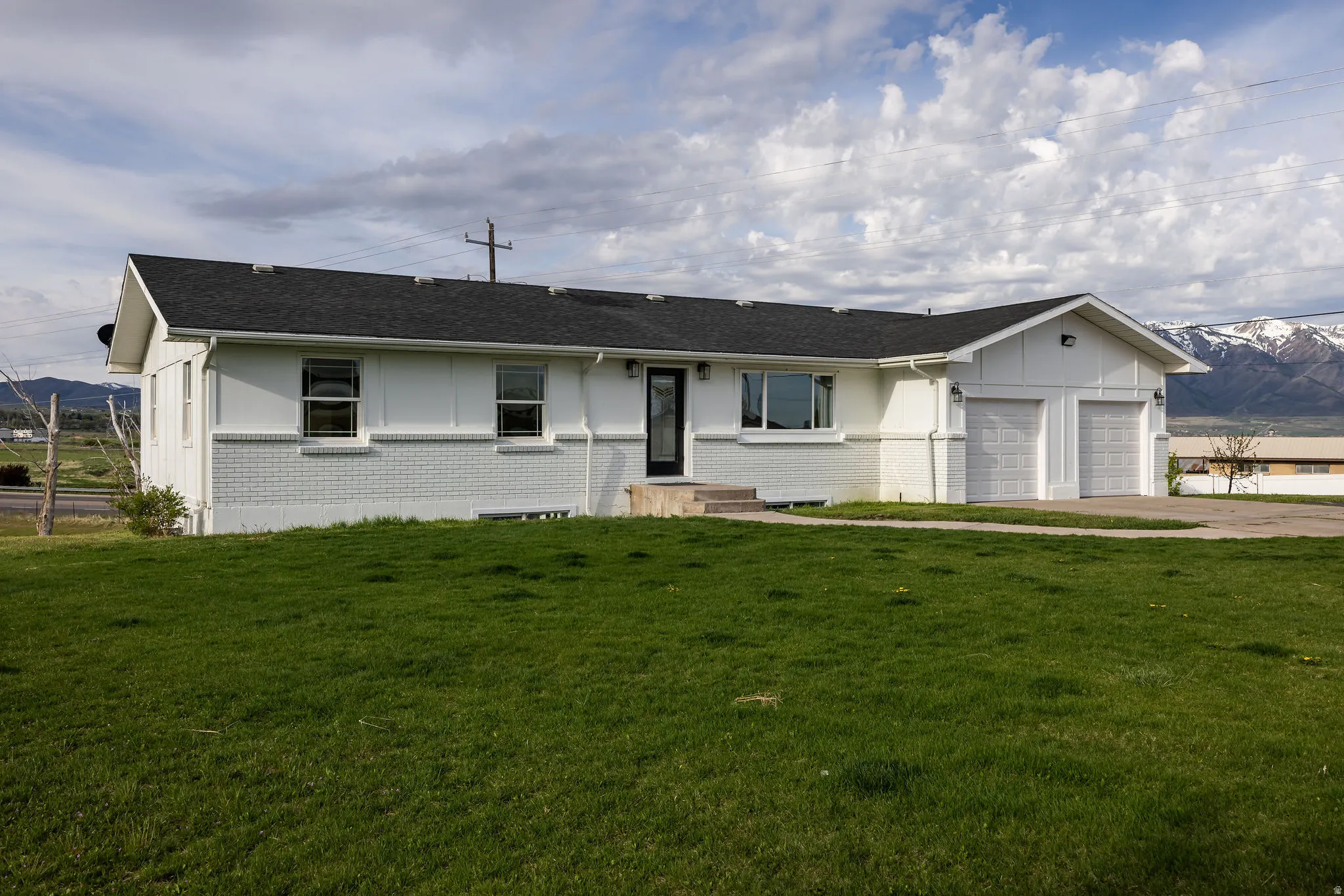 Ranch-style house featuring a mountain view, brick siding, an attached garage, and a front yard
