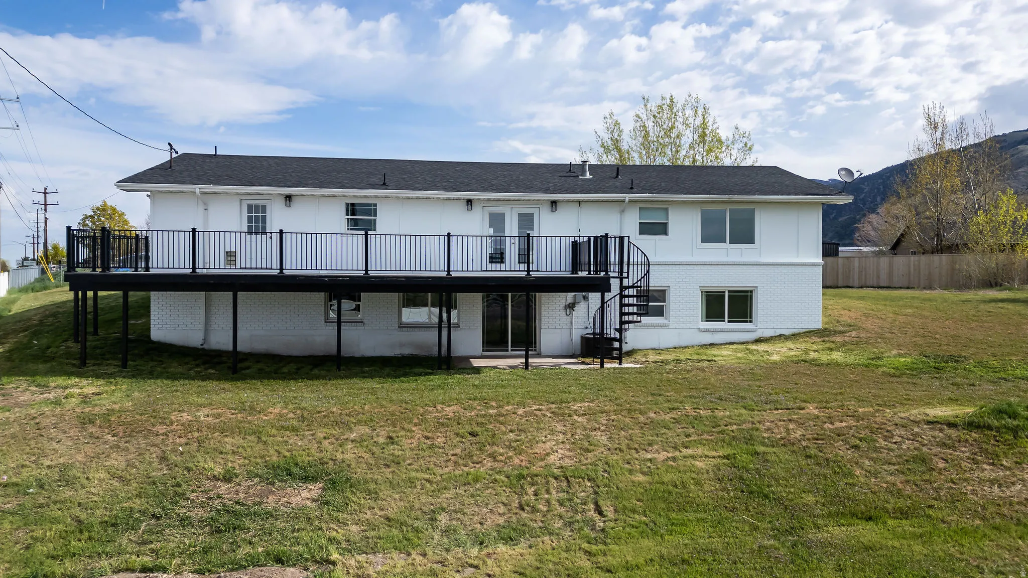 Back of property featuring a patio area, a deck, and brick siding
