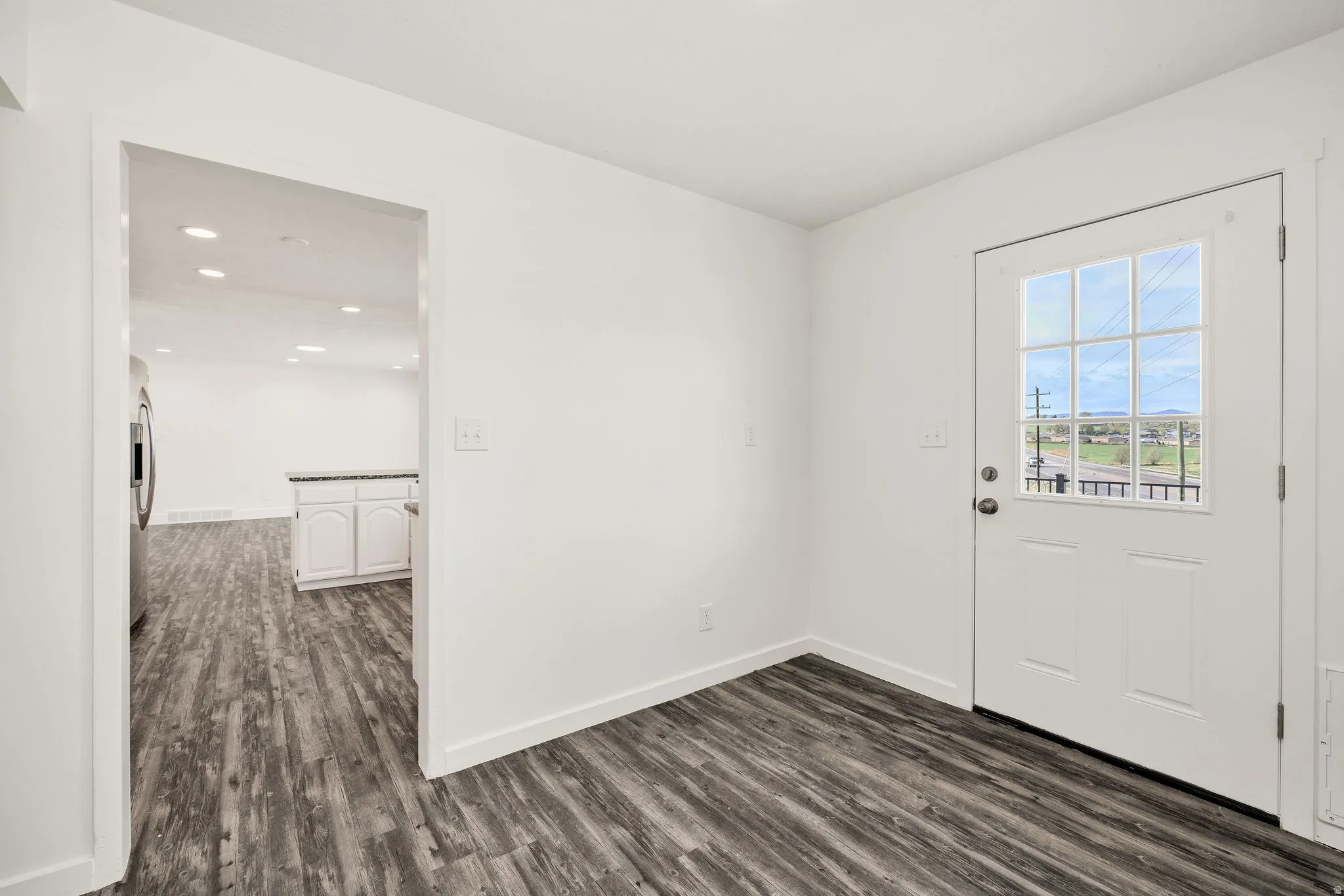 Interior space next to laundry room featuring wood finished floors and baseboards