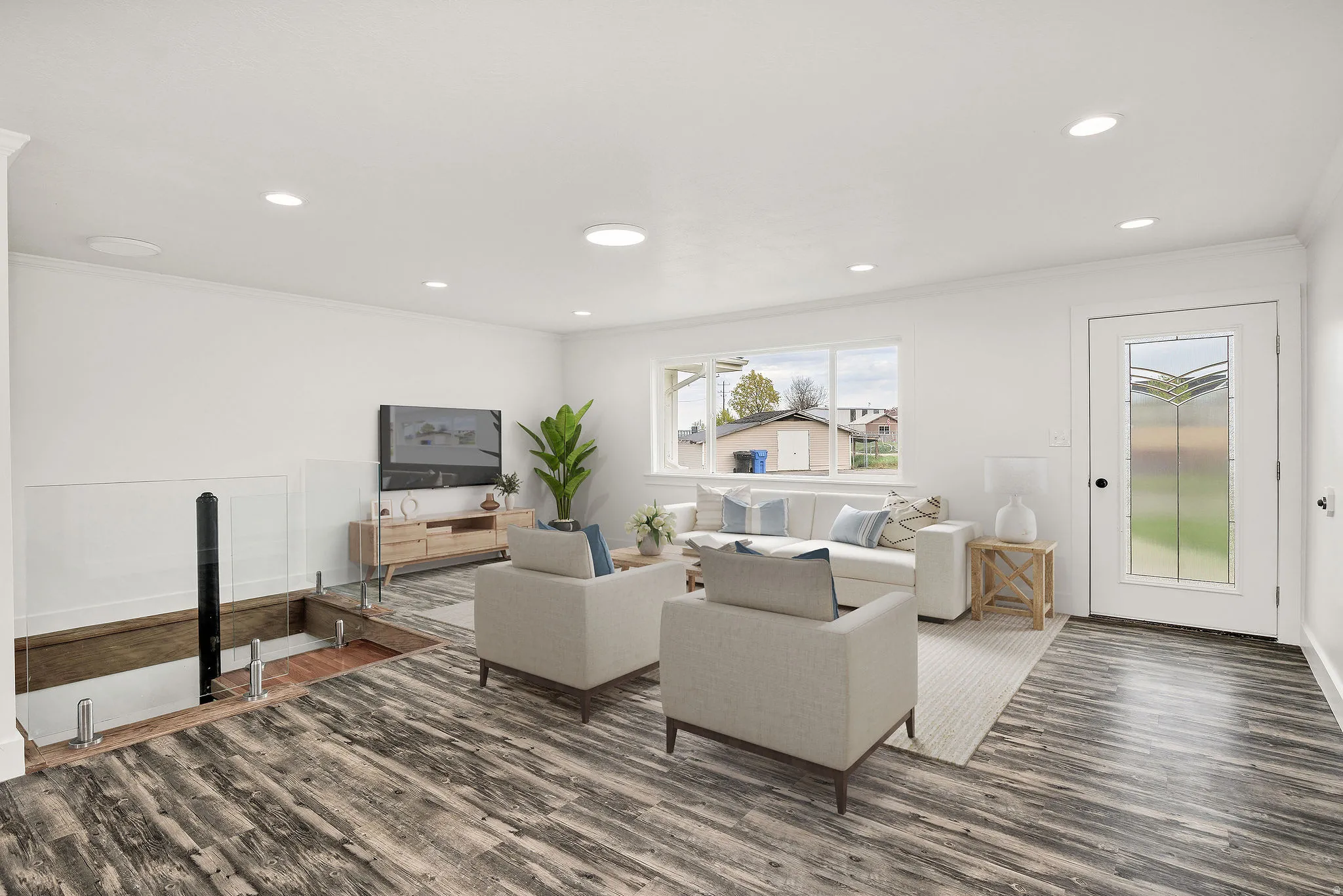 Virtually staged. Spacious living area featuring wood-finish flooring, recessed lighting, and a decorative glass-paneled entry door