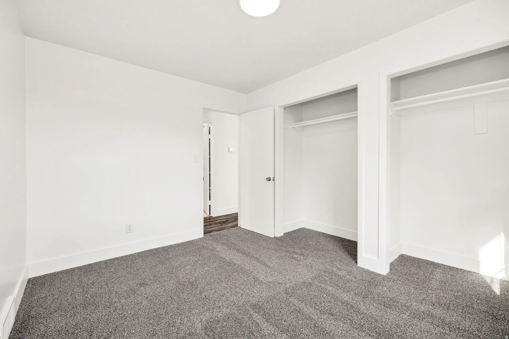 Unfurnished bedroom with dark colored carpet and two closets