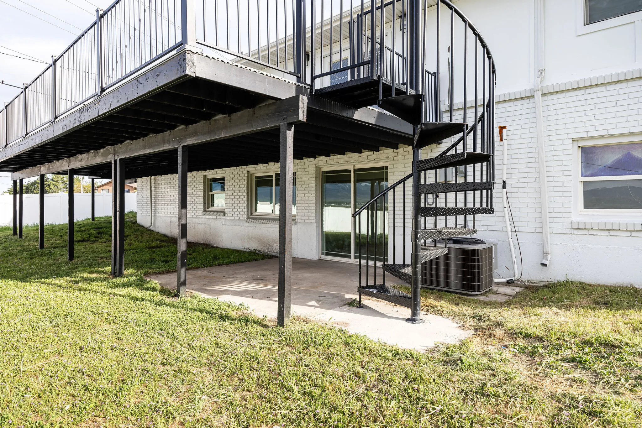 Back of property featuring a patio area, a lawn, brick siding, and a wooden deck