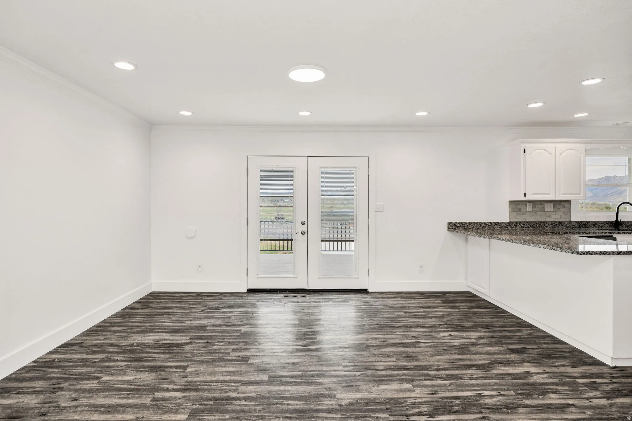 Kitchen featuring dark stone counters, dark wood finished floors, french doors, a peninsula, and healthy amount of natural light