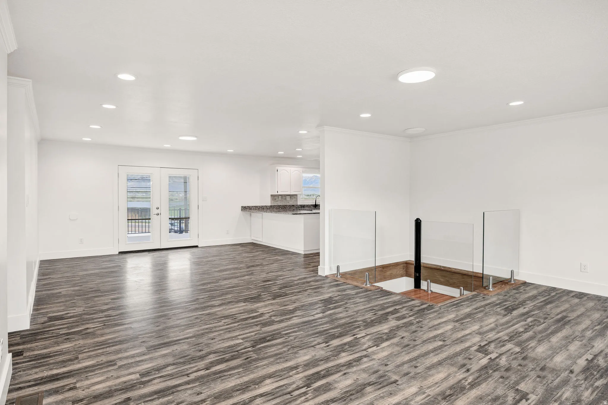Unfurnished living room featuring dark wood-type flooring, recessed lighting, and french doors