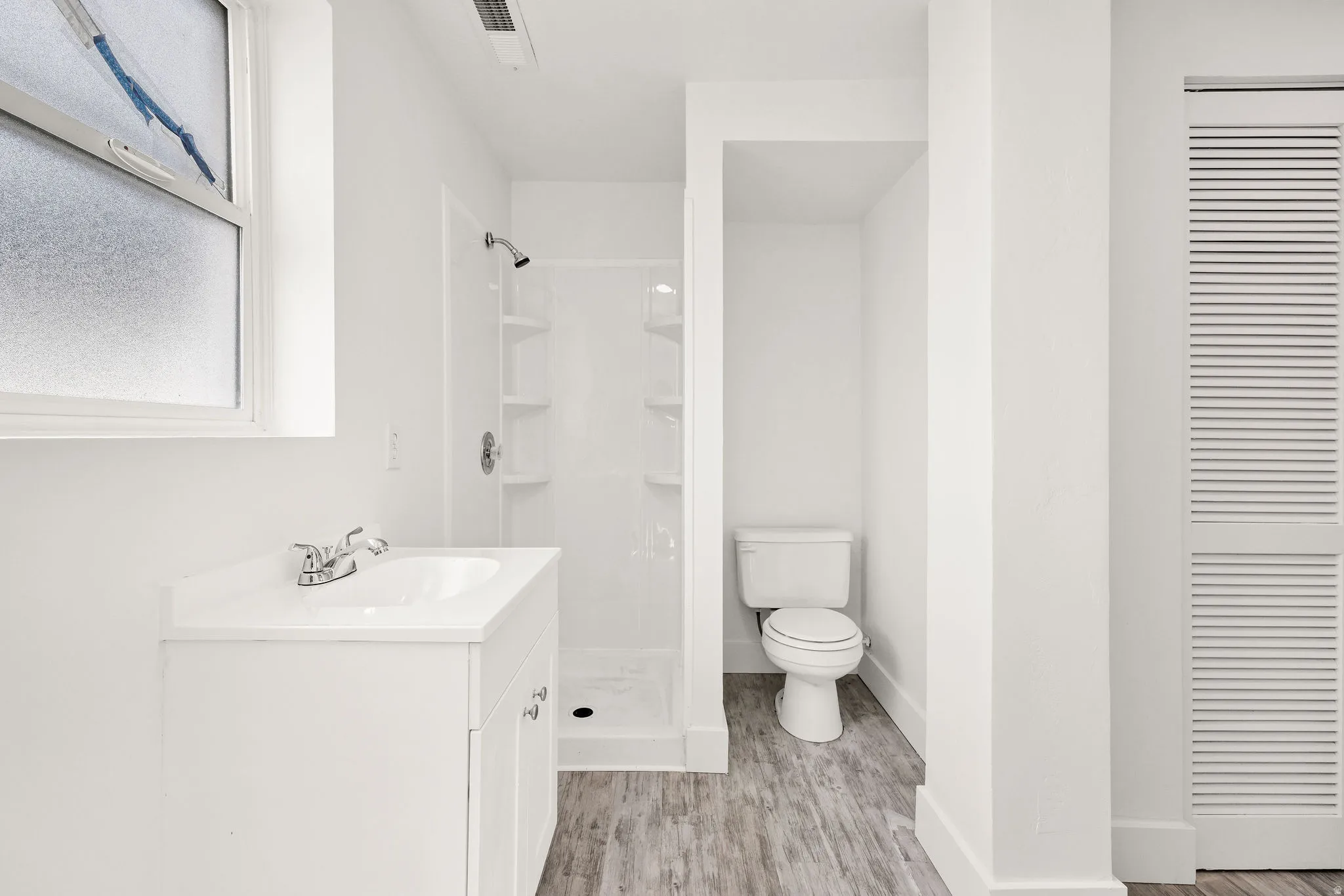 Full bathroom featuring vanity, a shower stall, light wood finished floors, and a closet
