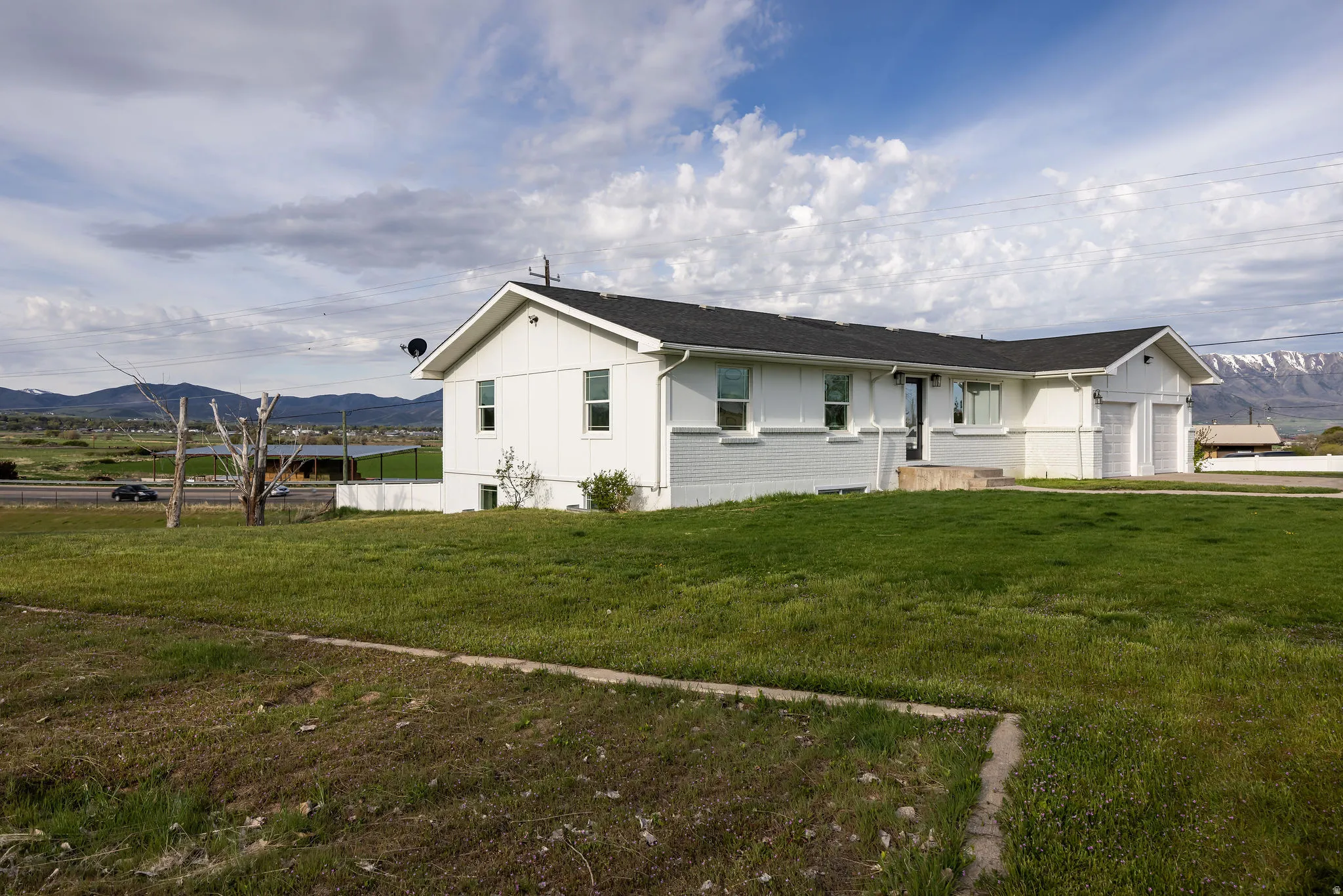 View of front of property with a mountain view, a front yard, and a garage